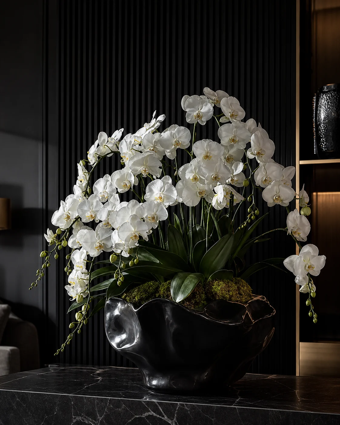 White orchids arranged in a glossy sculptural black vessel