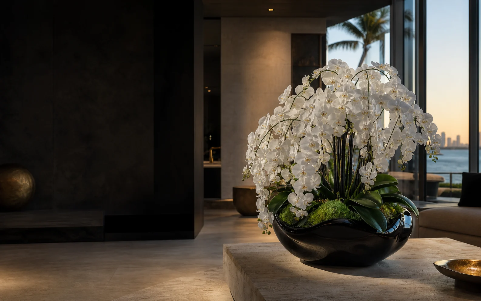 An abundant white orchid arrangement in a sculptural black vessel inside a Miami home